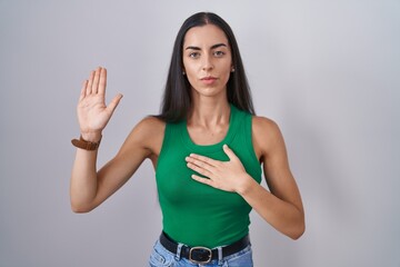 Sticker - Young woman standing over isolated background swearing with hand on chest and open palm, making a loyalty promise oath