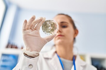 Poster - Young blonde woman wearing scientist uniform looking sample at laboratory