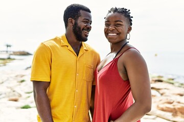 Poster - Young african american couple smiling happy standing at the beach.