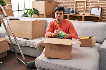 Canvas Print - Hispanic man moving to a new home unpacking depressed and worry for distress, crying angry and afraid. sad expression.