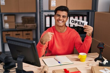 Sticker - Hispanic man working at small business ecommerce holding open banner pointing finger to one self smiling happy and proud