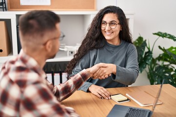 Wall Mural - Man and woman business workers shake hands at office