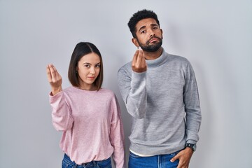 Poster - Young hispanic couple standing together doing italian gesture with hand and fingers confident expression