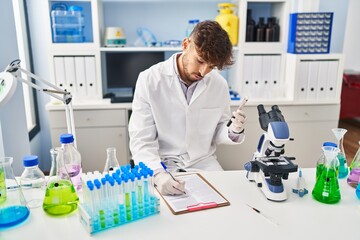 Poster - Young arab man scientist write on document analysing blood test tube at laboratory