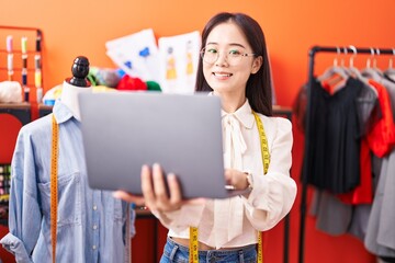 Poster - Young chinese woman tailor smiling confident using laptop at atelier