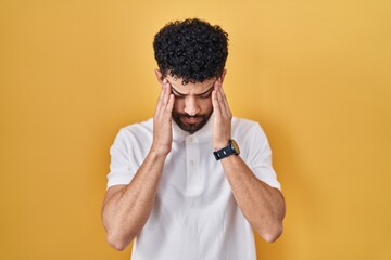 Sticker - Arab man standing over yellow background with hand on head, headache because stress. suffering migraine.