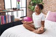 © Krakenimages.com - African american woman doing yoga exercise sitting on bed at bedroom