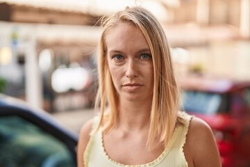 Poster - Young blonde woman with relaxed expression standing at street