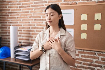 Poster - Chinese young woman working at the office doing presentation smiling with hands on chest with closed eyes and grateful gesture on face. health concept.