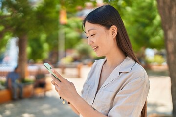 Wall Mural - Chinese woman smiling confident using smartphone at park