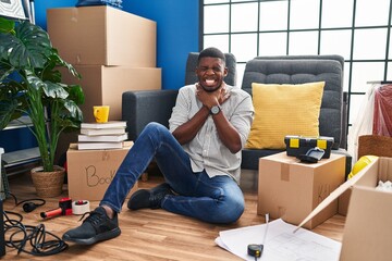 Poster - African american man sitting on the floor at new home shouting suffocate because painful strangle. health problem. asphyxiate and suicide concept.