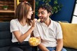 Man and woman smiling confident eating chips potatoes at home