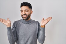 Hispanic Man With Beard Standing Over White Background Smiling Showing Both Hands Open Palms, Presenting And Advertising Comparison And Balance