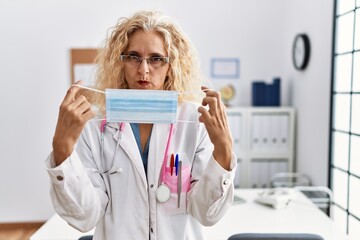 Sticker - Middle age blonde woman wearing doctor uniform and medical mask skeptic and nervous, frowning upset because of problem. negative person.