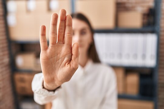 Young caucasian woman ecommerce business worker doing stop gesture with hand at office