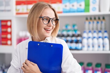 Sticker - Young blonde woman pharmacist smiling confident holding clipboard at pharmacy