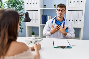 Sticker - Young doctor with client at medical clinic smiling with hands on chest with closed eyes and grateful gesture on face. health concept.