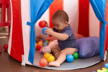 Adorable Chinese Toddler Playing With Balls Sitting Inside Of Circus Tent At Home