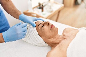 Wall Mural - Middle age man and woman wearing therapist uniform having anti aging treatment at beauty center