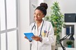 © Krakenimages.com - African american woman wearing doctor uniform using touchpad working at clinic