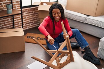 Wall Mural - African american woman smiling confident repair chair at new home