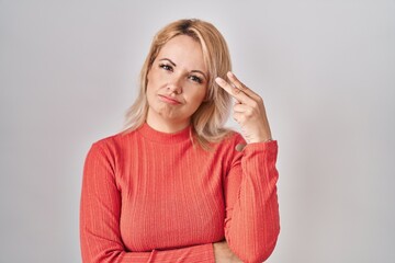 Canvas Print - Blonde woman standing over isolated background shooting and killing oneself pointing hand and fingers to head like gun, suicide gesture.