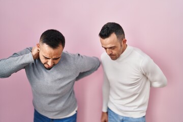 Sticker - Homosexual couple standing over pink background suffering of backache, touching back with hand, muscular pain