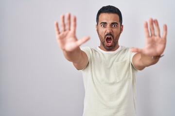 Sticker - Hispanic man with beard standing over isolated background doing stop gesture with hands palms, angry and frustration expression