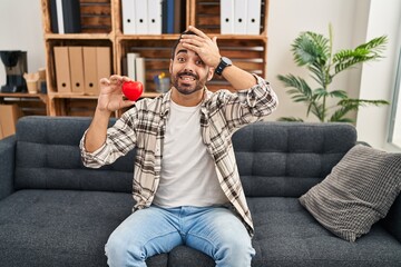 Canvas Print - Young hispanic man with beard working on love therapy at consultation office stressed and frustrated with hand on head, surprised and angry face