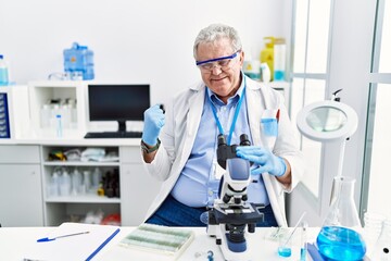 Sticker - Senior caucasian man working at scientist laboratory very happy and excited doing winner gesture with arms raised, smiling and screaming for success. celebration concept.