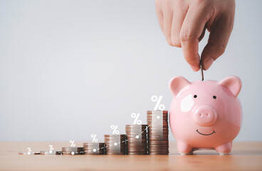 Wall Mural - Businessman putting coin to pink piggy bank with increasing coins stacking on table , Money saving and deposit for investment to get profit and dividend concept.