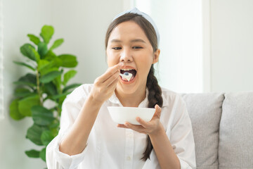 Healthy lifestyle, wellness food asian young woman hand use spoon eat tasty fresh organic yogurt, dairy product in bowl breakfast meal at home. Snack tasty on diet nutrition delicious natural yoghurt