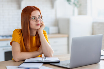 Wall Mural - Beautiful young female student after the online webinar, dreams, looks away and smiles sweetly. Online education or remote work at home