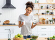 © kucherav - Happy African American woman in home kitchen holding a bottle of nutritional supplements and smiling friendly, healthy lifestyle