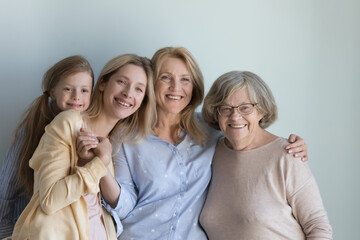 Loving multi-generational family portrait. Different age generation women, older and younger relatives female pose on blue studio background, hugging, feeling connection, showing unity, love and care