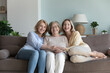 Portrait happy three generations women pose for family picture sit on sofa. Smiling granny, mature daughter and young adult granddaughter looking at camera, feel love, having warm family relationship