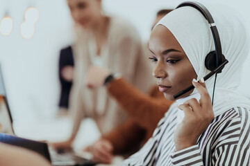 African American muslim woman with hijab and headset working as customer support in a modern office.