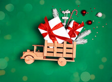 Wooden Toy Truck With Christmas Gifts And Decorations On Green Background.
