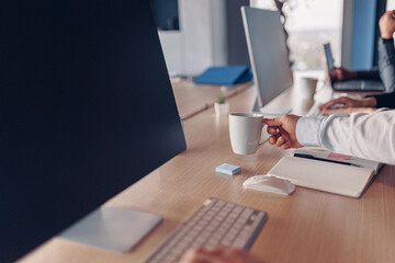 Wall Mural - Businessman hands holding cup of coffee while sitting on his workplace in office