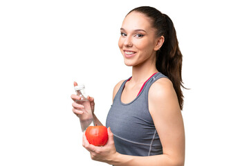 Wall Mural - Young caucasian woman over isolated background with an apple and with a bottle of water