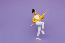 Full Body Side View Fun Young Housekeeper Woman Wear Yellow Shirt Tidy Up Hold Broom Sweeping Brush Look Aside Clean House Isolated On Plain Pastel Light Purple Background Studio. Housework Concept.