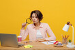 © ViDi Studio - Young serious employee business woman in casual shirt sit work at office desk with pc laptop look through magnifier reading-glass isolated on plain yellow color background Achievement career concept