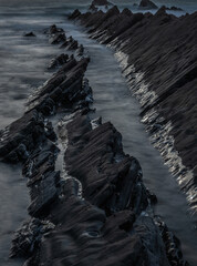 Wall Mural - Abstract landscape picture of rocks on Welcome Mouth Beach at sunset with tide marks on rocks reflecting sunlight