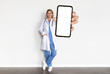 © Prostock-studio - Medical Ad. Doctor Lady In Uniform Holding Big Blank Smartphone In Hand