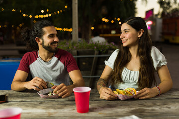 Excited couple eating mexican food at nigh from the food cart