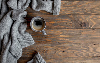 cozy winter or autumn composition with  grey sweater and a cup of coffee on a wooden background. copy space. top view. flat lay style