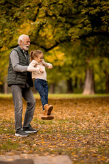 Wall Mural - Grandfather spending time with his granddaughter in park on autumn day