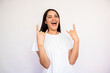 © KAMPUS - Portrait of excited young woman making rock and roll gesture over white background. Caucasian lady wearing white T-shirt looking at camera and laughing. Music fan concept