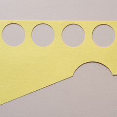 Sticker - yellow paper with circle cutouts on blank beige paper