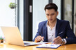 © Wasan - Businessman working on document on laptop in office.